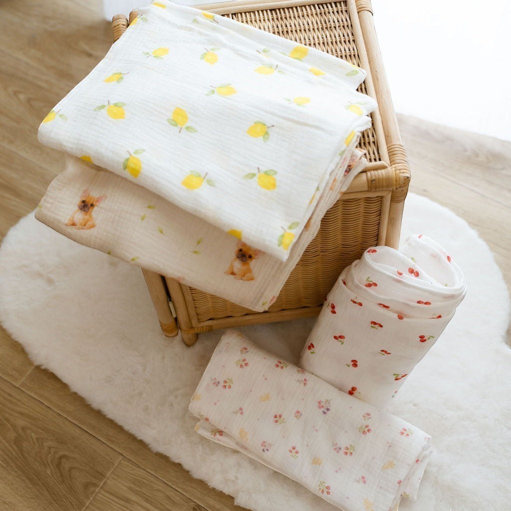 Baby Natur muslin tetra swaddle blankets with lemon, French bulldog, cherry, and floral prints. 100% breathable cotton.