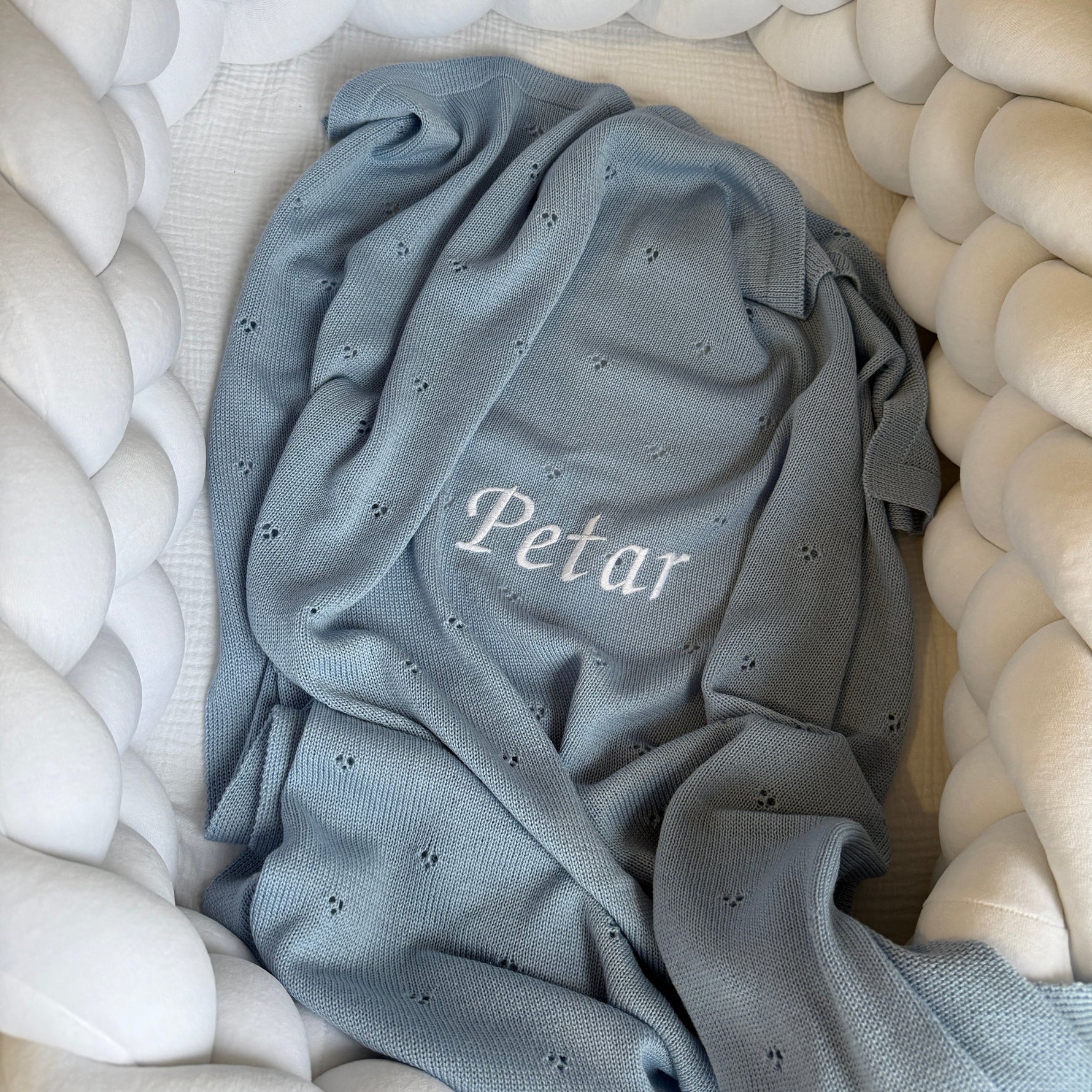 Gray baby blanket with 'Petar' embroidery on a white textured surface