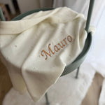 White fabric with 'Mauro' embroidery on a chair