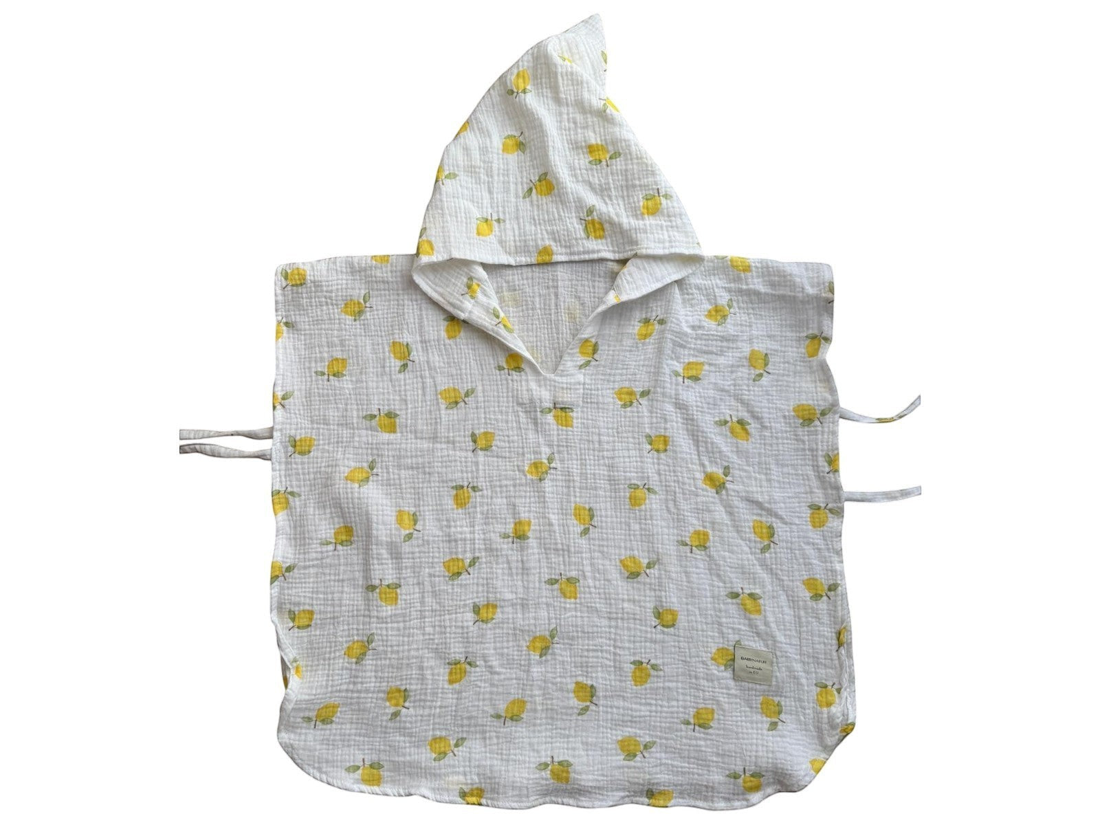 Baby Natur white muslin baby poncho with yellow lemon print and hood. Features tie closures on sides.