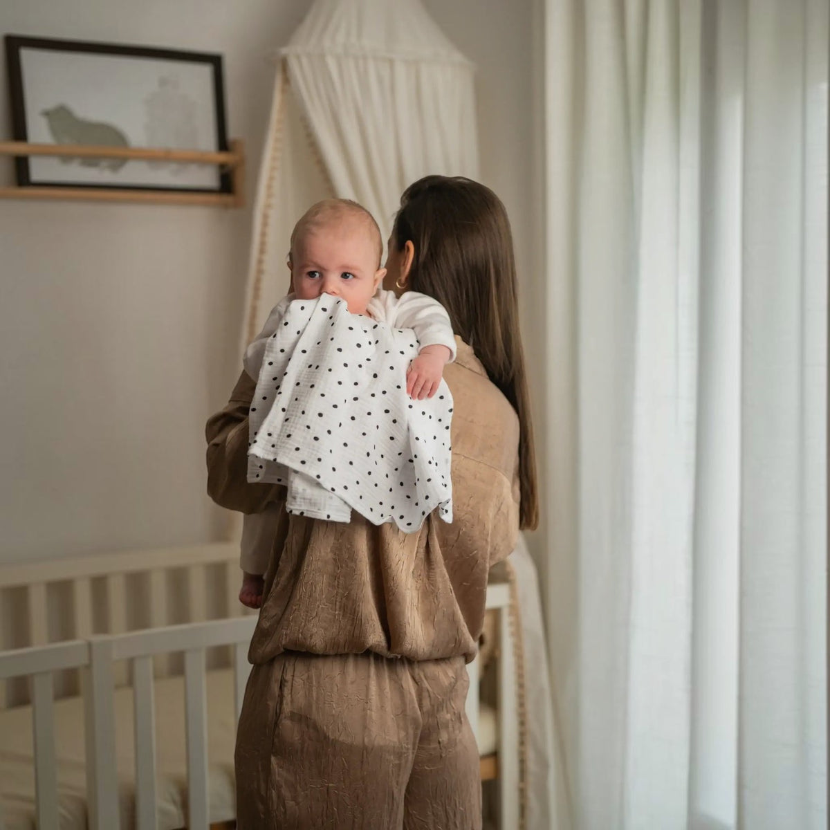Baby NaturHere standard tetra diaper made of 100% cotton with black polka dots, used by a mother to burp her baby.